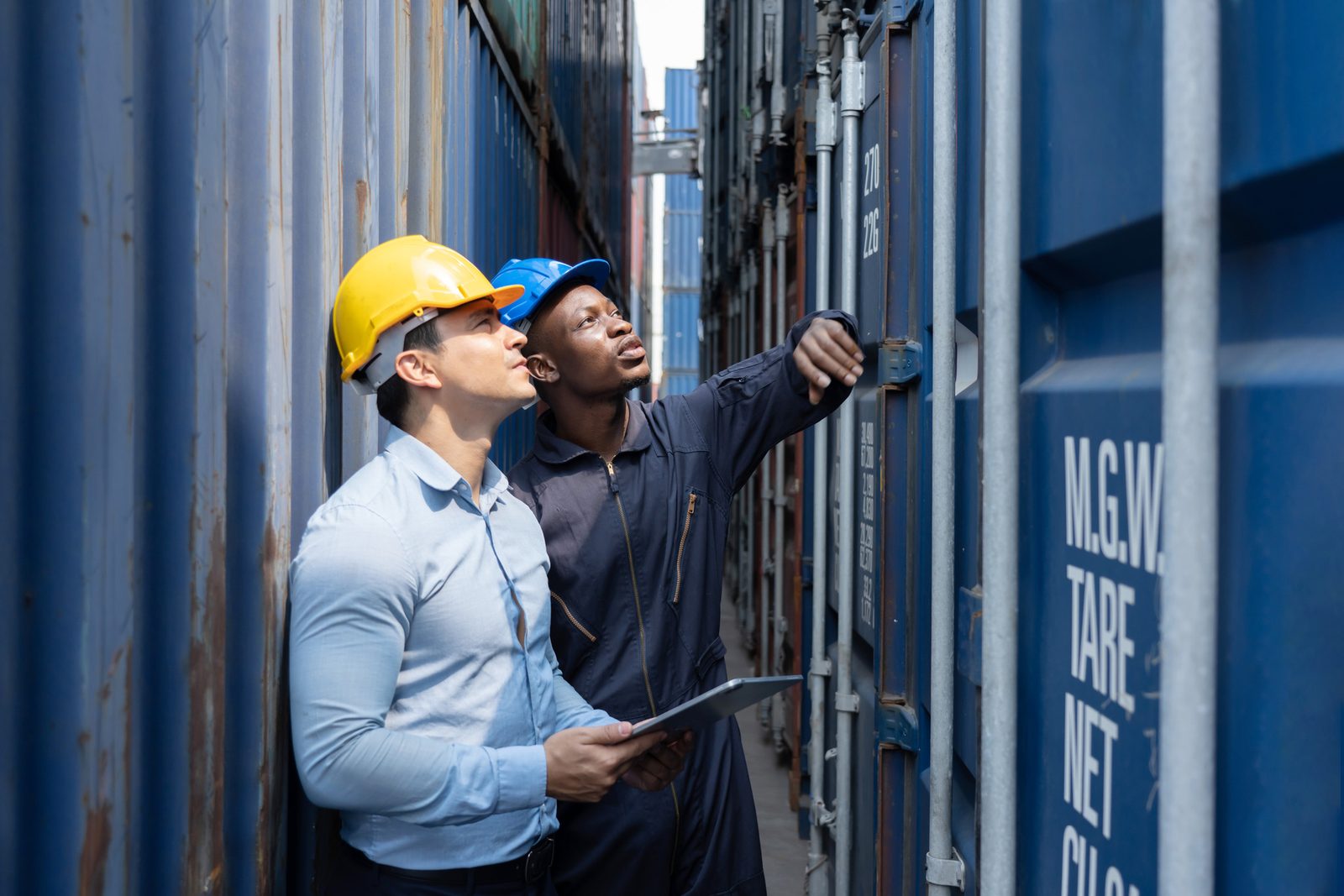 Two logistics workers inspecting shipping containers